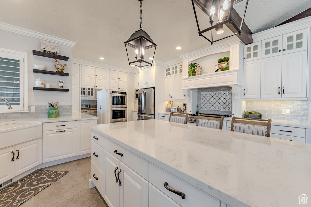Kitchen with open shelves, decorative backsplash, a sink, a notable chandelier, and appliances with stainless steel finishes