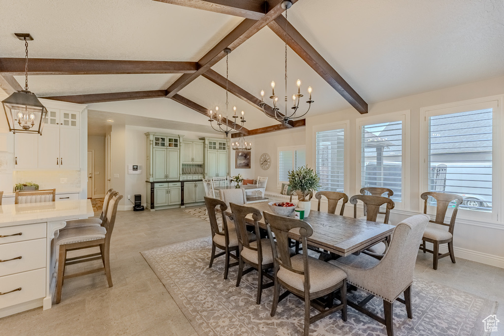 Dining area featuring baseboards, a notable chandelier, and lofted ceiling with beams
