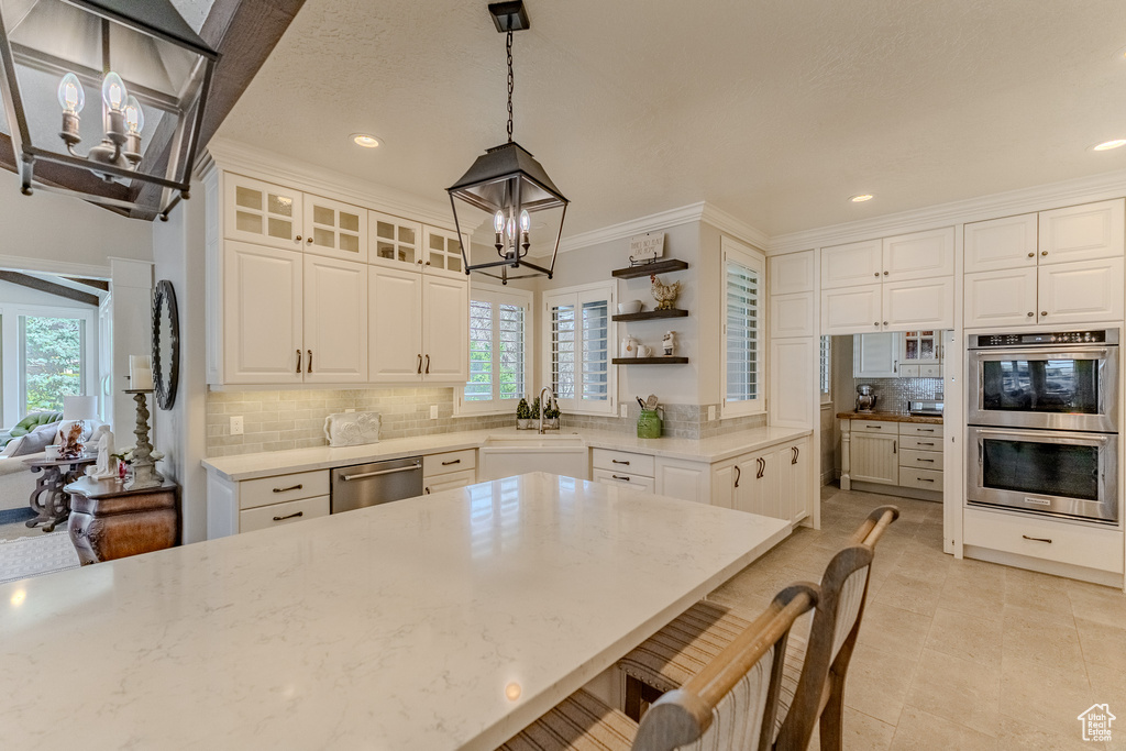 Kitchen with white cabinetry, stainless steel appliances, a notable chandelier, and open shelves