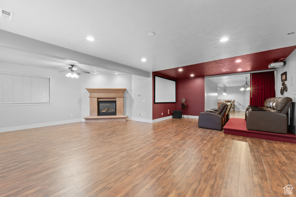 Living room with a ceiling fan, wood finished floors, a glass covered fireplace, recessed lighting, and baseboards