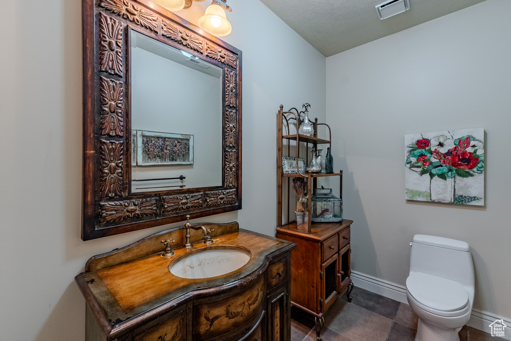 Bathroom with baseboards, visible vents, toilet, and vanity