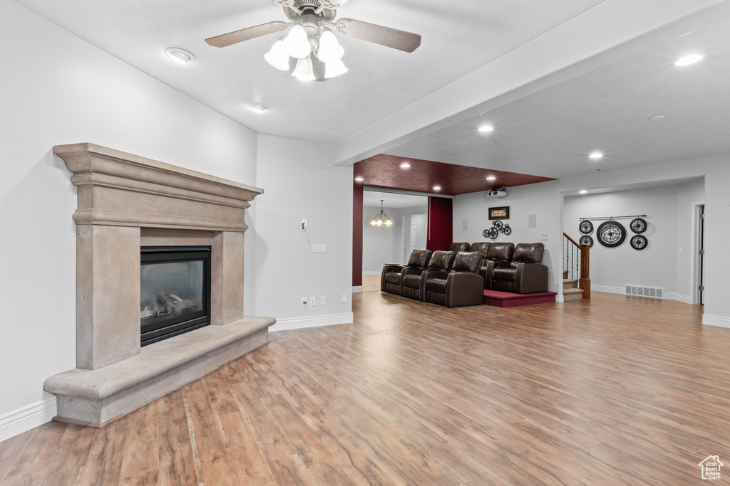 Living room with wood finished floors, ceiling fan, baseboards, a fireplace, and recessed lighting