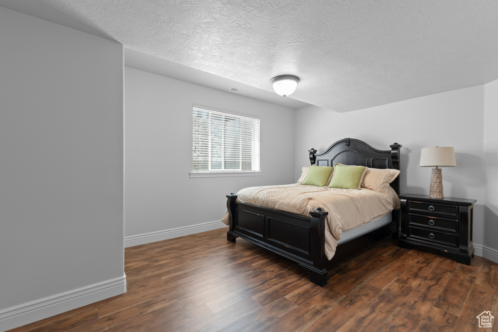 Bedroom with a textured ceiling, wood finished floors, and baseboards