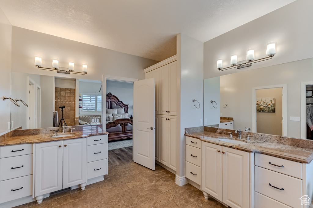 Bathroom with a tile shower, a sink, and two vanities