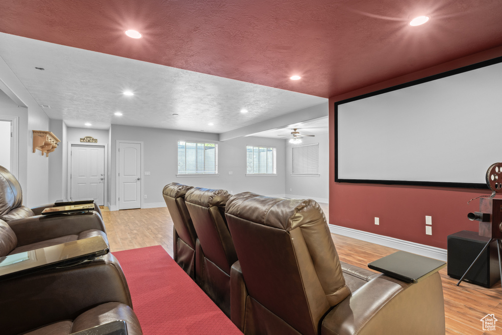 Cinema room featuring light wood-style floors, baseboards, a ceiling fan, recessed lighting, and a textured ceiling
