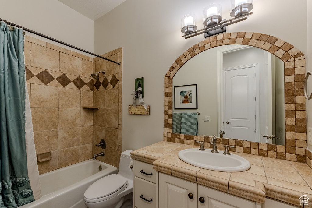 Bathroom with a notable chandelier, toilet, vanity, and shower / bathtub combination with curtain