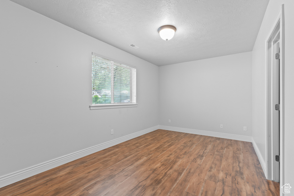 Unfurnished bedroom featuring wood finished floors, a textured ceiling, and baseboards
