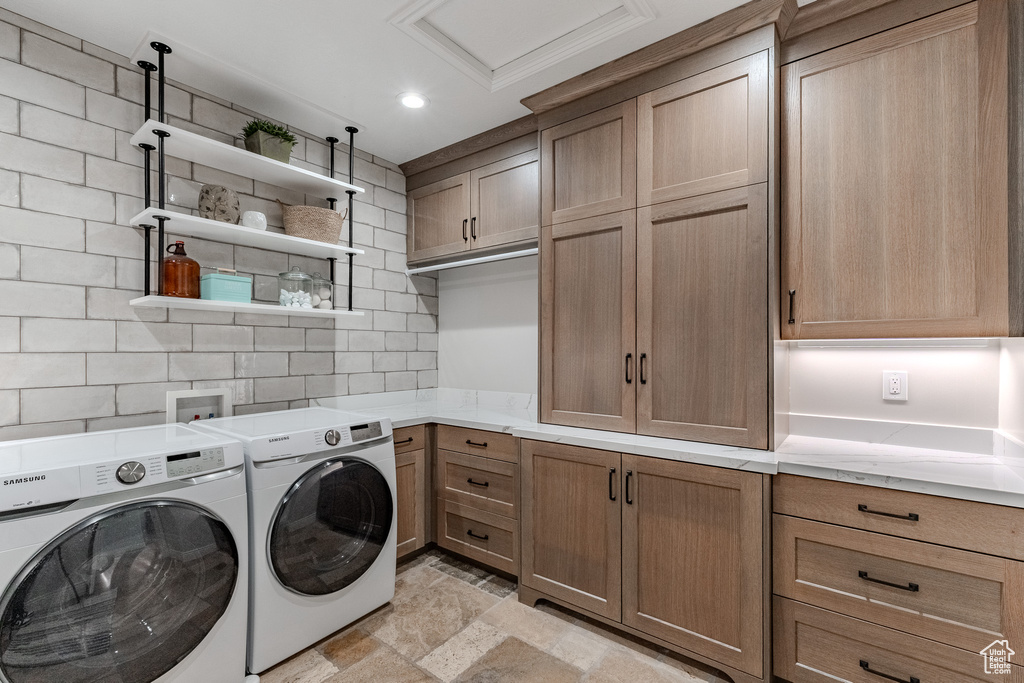Washroom featuring attic access, recessed lighting, stone tile flooring, cabinet space, and washing machine and dryer