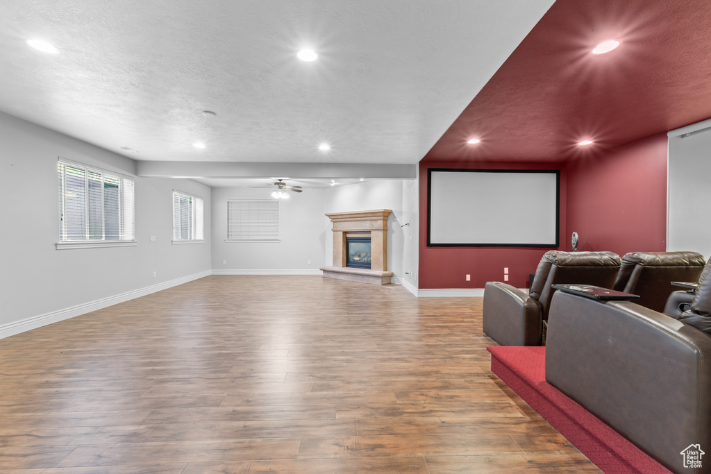 Cinema room with recessed lighting, wood finished floors, baseboards, ceiling fan, and a glass covered fireplace