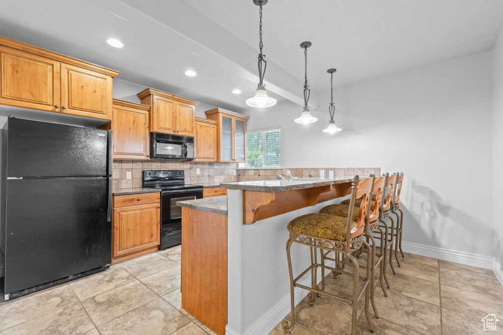 Kitchen featuring black appliances, a kitchen breakfast bar, backsplash, glass insert cabinets, and decorative light fixtures
