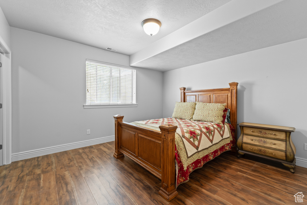 Bedroom featuring dark wood-type flooring, baseboards, and a textured ceiling