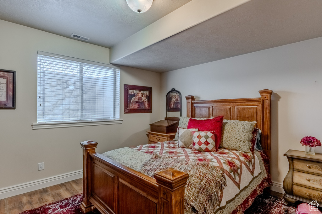 Bedroom with baseboards, visible vents, and wood finished floors