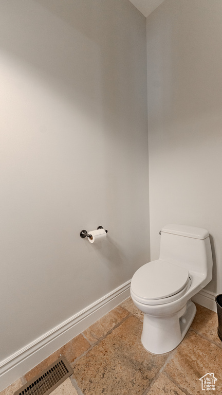 Bathroom featuring baseboards, visible vents, toilet, and stone tile flooring