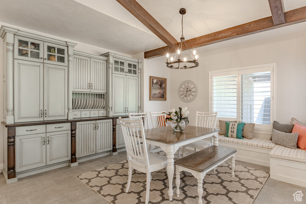 Dining area with an inviting chandelier and beam ceiling