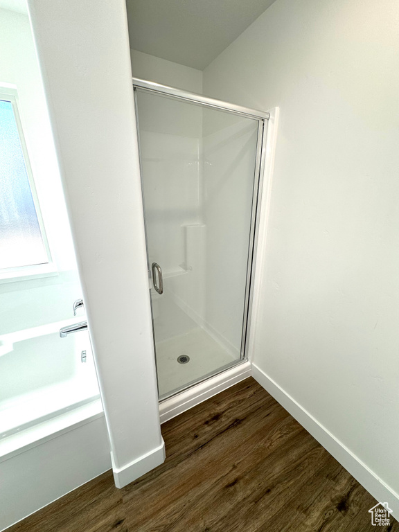 Full bath with a stall shower, baseboards, and wood finished floors