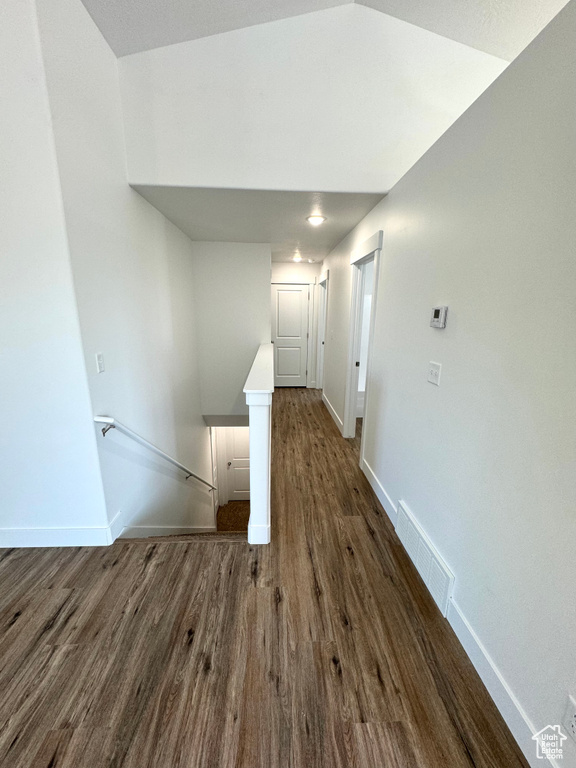 Corridor featuring baseboards, an upstairs landing, visible vents, and dark wood finished floors