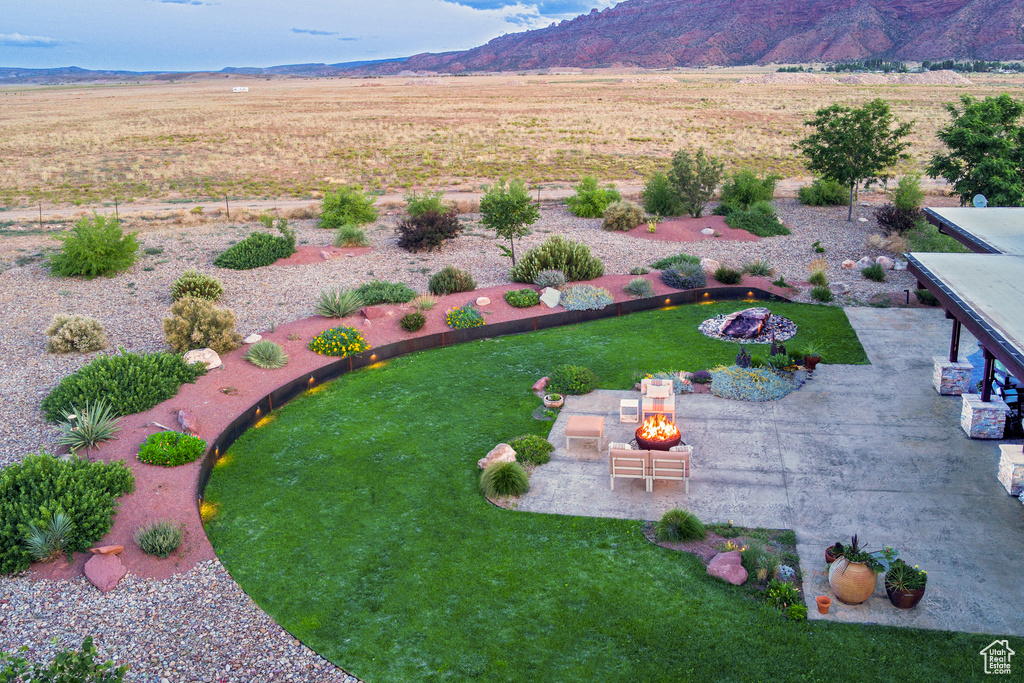 View of grassy yard with a mountain view, a patio area, and a fire pit