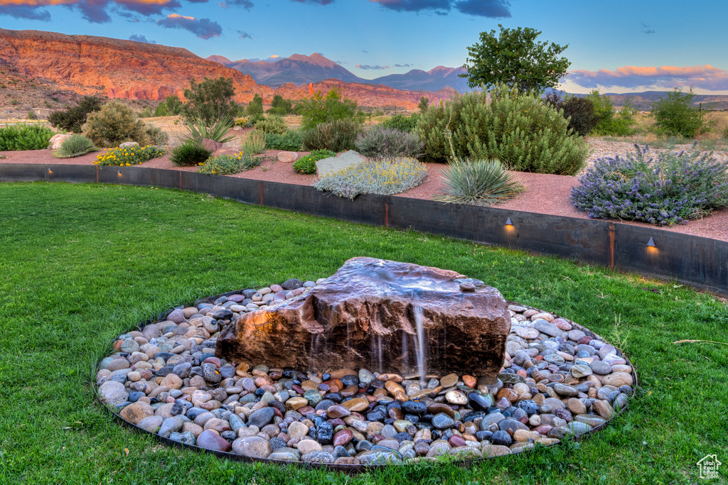 Yard at dusk featuring a lawn and a mountain view