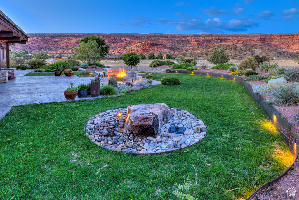 View of grassy yard featuring a fire pit, a patio area, and a mountain view
