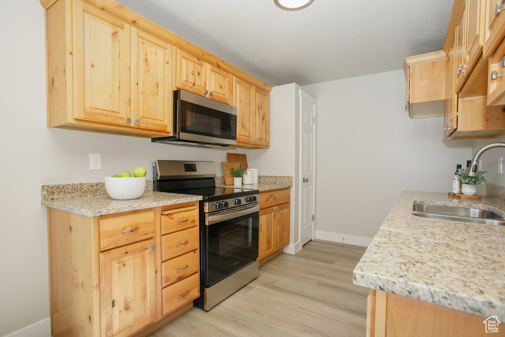 Kitchen featuring light brown cabinets, light wood-style flooring, a sink, and appliances with stainless steel finishes