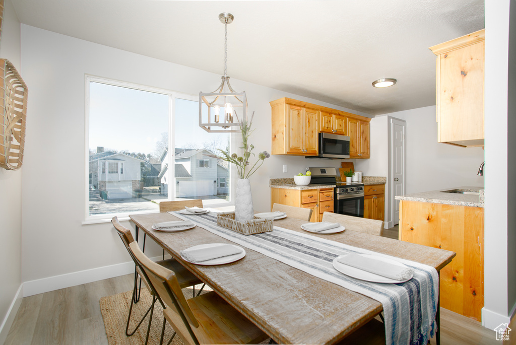 Dining space featuring baseboards, a chandelier, and light wood-type flooring