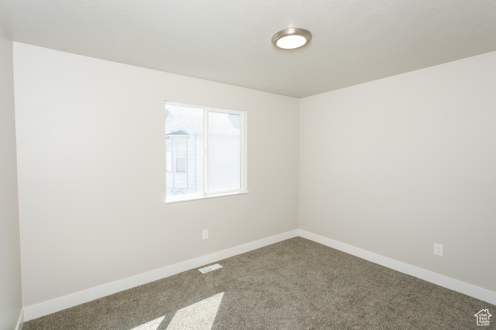 Carpeted empty room with baseboards and visible vents
