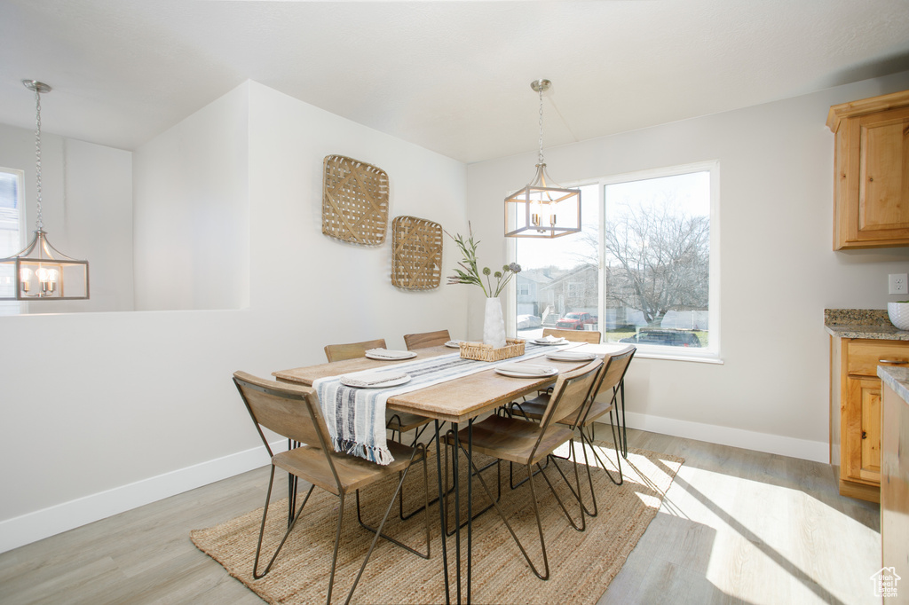 Dining area with an inviting chandelier, light wood-style flooring, baseboards, and a healthy amount of sunlight