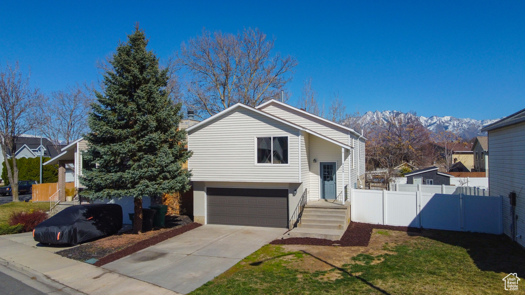 View of front of house with driveway, an attached garage, fence, and a mountain view