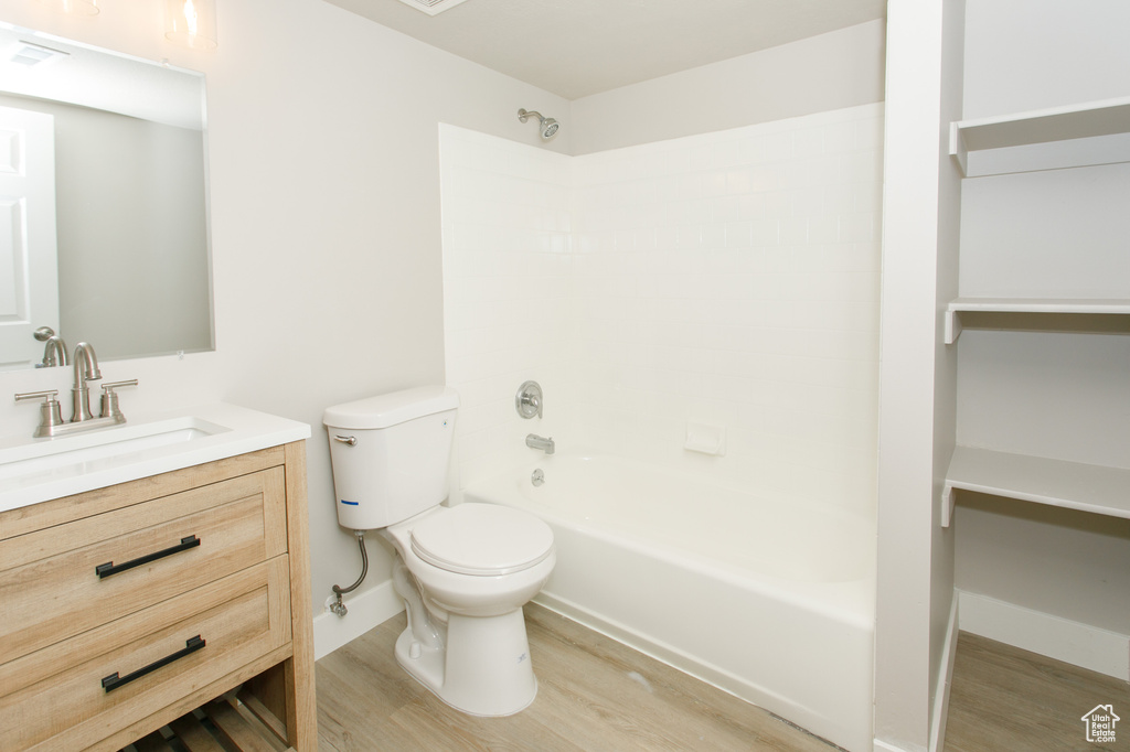 Full bath with visible vents, wood finished floors, toilet, vanity, and shower / bathing tub combination
