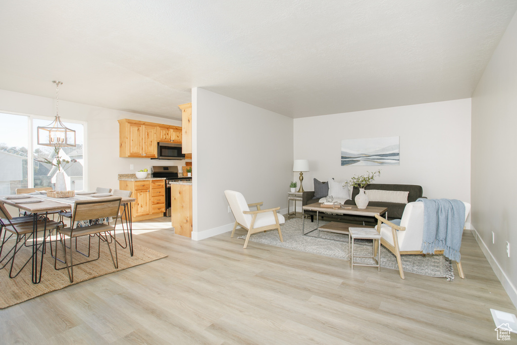 Dining area with light wood finished floors, baseboards, and a chandelier