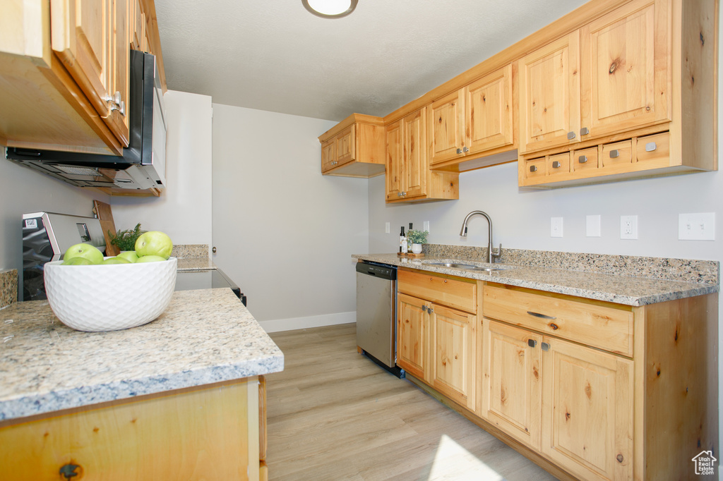 Kitchen with baseboards, stainless steel dishwasher, a sink, light wood-style floors, and light brown cabinets