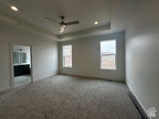 Unfurnished bedroom featuring a raised ceiling, carpet floors, and baseboards