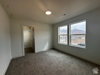 Unfurnished bedroom featuring baseboards, carpet floors, visible vents, and a walk in closet