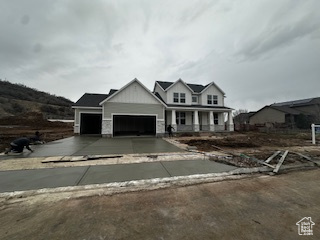 View of front of house featuring an attached garage, concrete driveway, and a porch