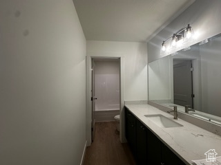Bathroom featuring toilet, vanity, baseboards, and wood finished floors