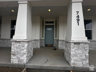 View of exterior entry with a porch and stone siding