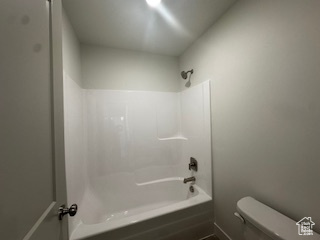 Full bath featuring toilet and washtub / shower combination