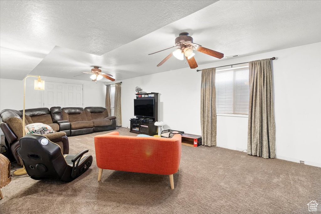 Living room featuring carpet floors, a textured ceiling, and a ceiling fan