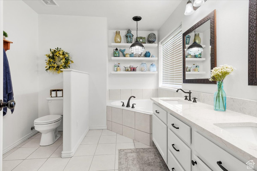 Full bath with double vanity, toilet, tile patterned floors, a sink, and a garden tub