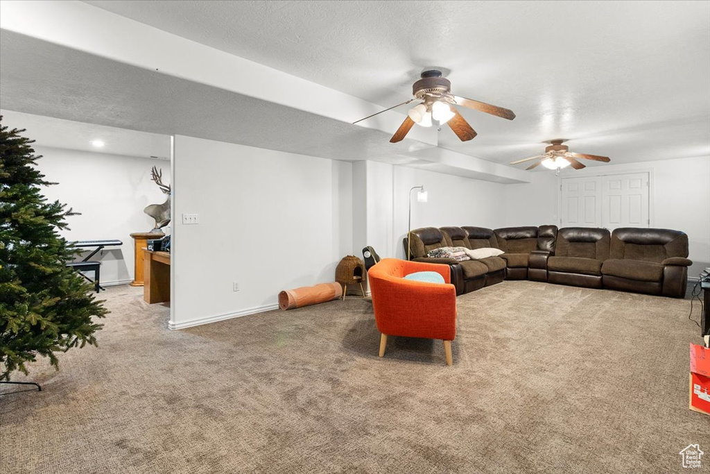 Carpeted living room featuring baseboards and ceiling fan