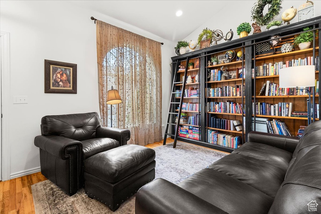 Sitting room with baseboards, wood finished floors, vaulted ceiling, and recessed lighting
