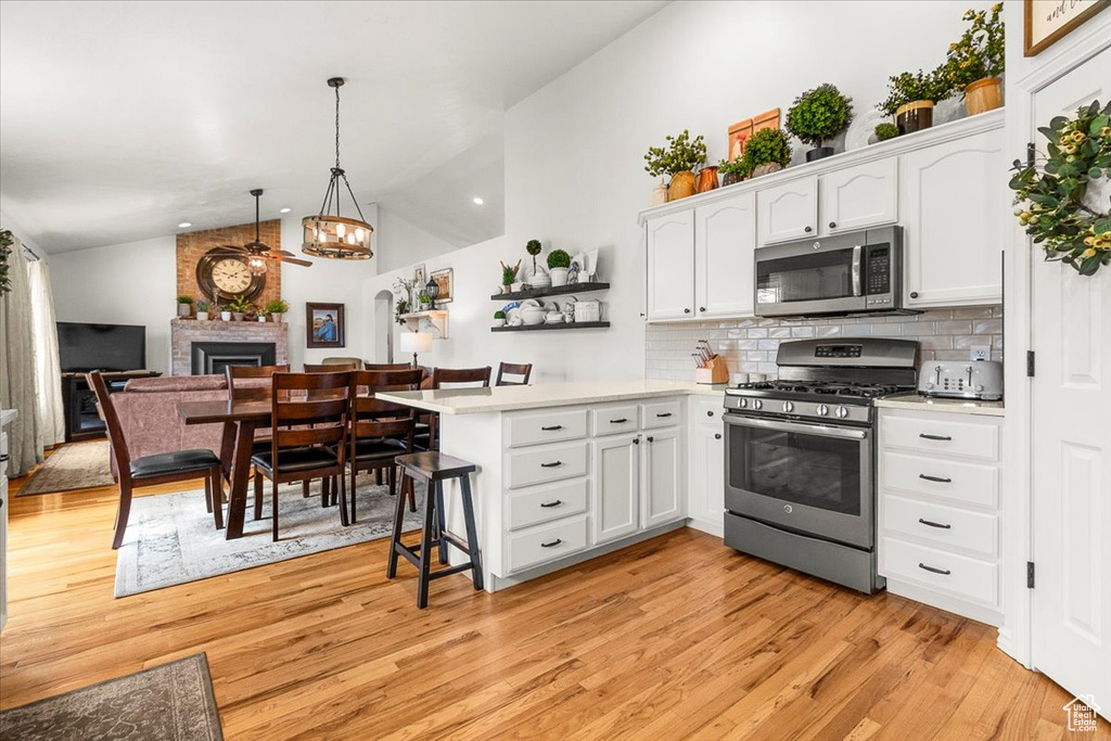 Kitchen with light countertops, white cabinets, a peninsula, stainless steel appliances, and a ceiling fan