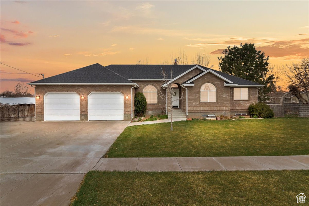 Ranch-style house featuring roof with shingles, concrete driveway, an attached garage, brick siding, and a front lawn