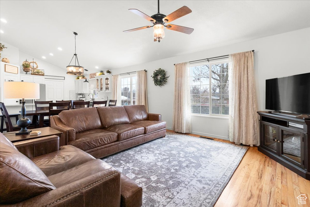 Living area featuring vaulted ceiling, recessed lighting, ceiling fan with notable chandelier, light wood-style floors, and visible vents
