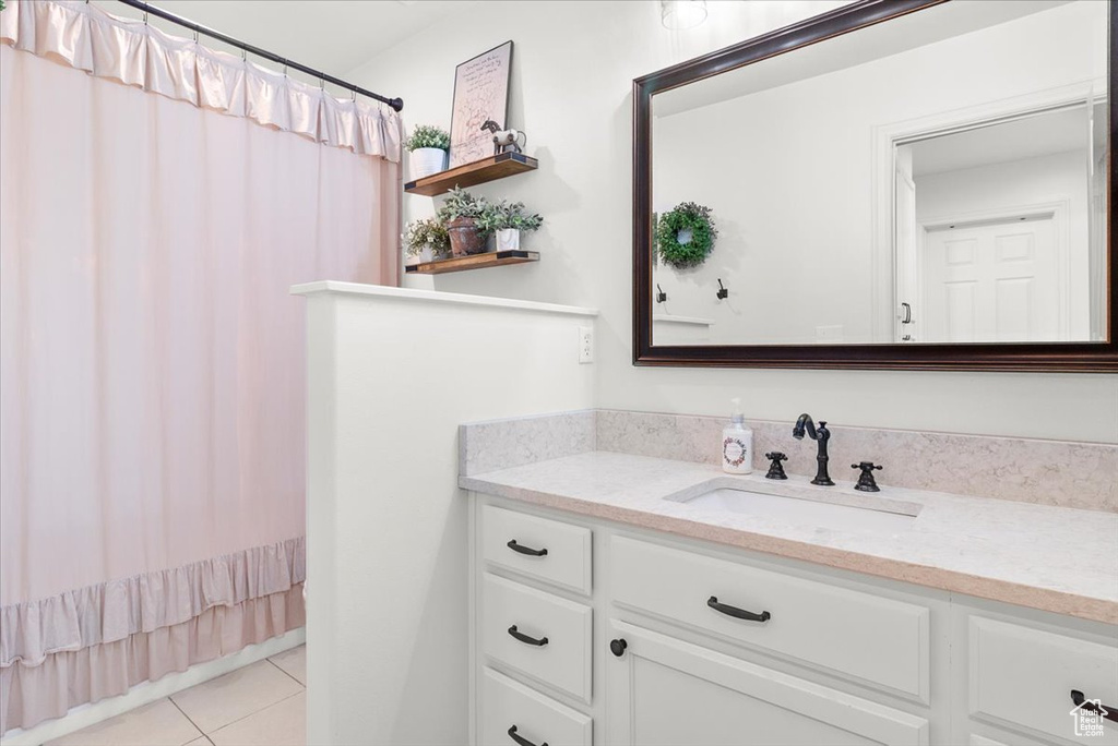 Bathroom with tile patterned floors, a shower with shower curtain, and vanity