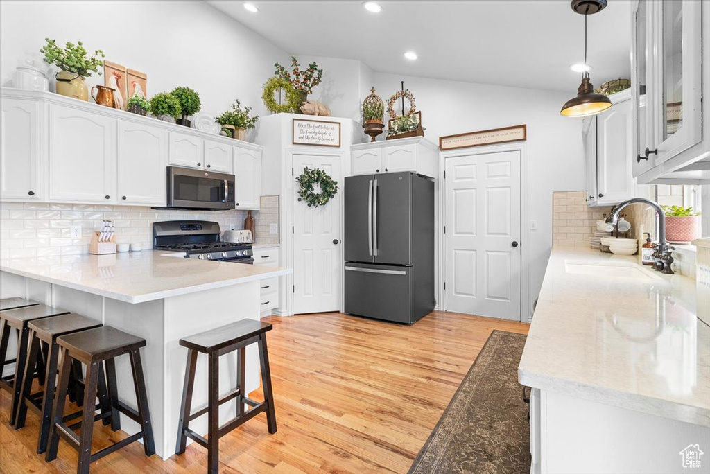 Kitchen featuring white cabinetry, a sink, stainless steel appliances, and a peninsula