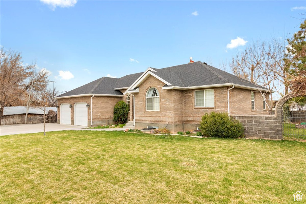 View of front of home featuring brick siding, a garage, concrete driveway, and a front yard