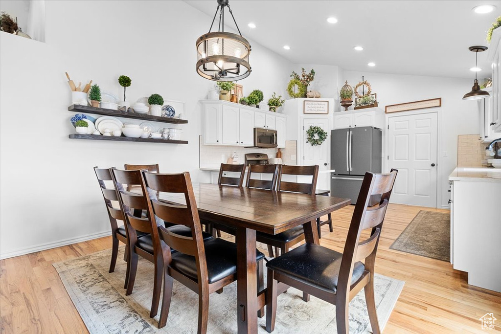 Dining room featuring high vaulted ceiling, light wood-style floors, recessed lighting, and a chandelier