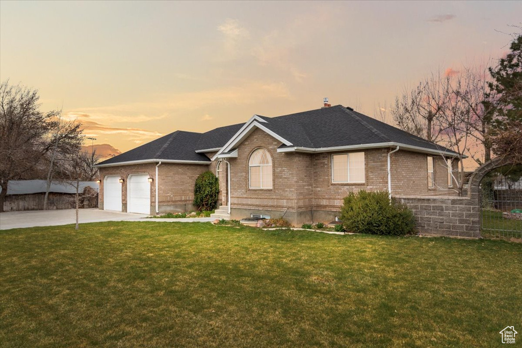 Ranch-style house with concrete driveway, fence, an attached garage, brick siding, and a lawn