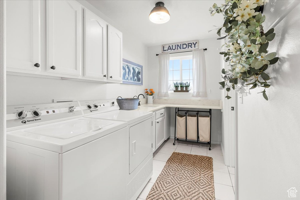 Clothes washing area with a sink, washing machine and clothes dryer, light tile patterned flooring, and cabinet space